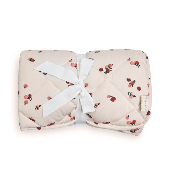 A quilted baby play mat, peaches print on one side, and plain burnt orange colour on the reverse.