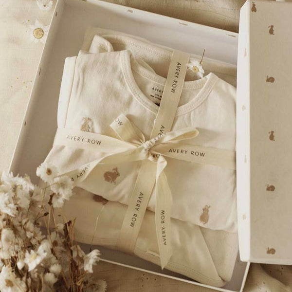 A new baby gift set which includes a baby sleepsuit and baby blanket with embroidered bunnies