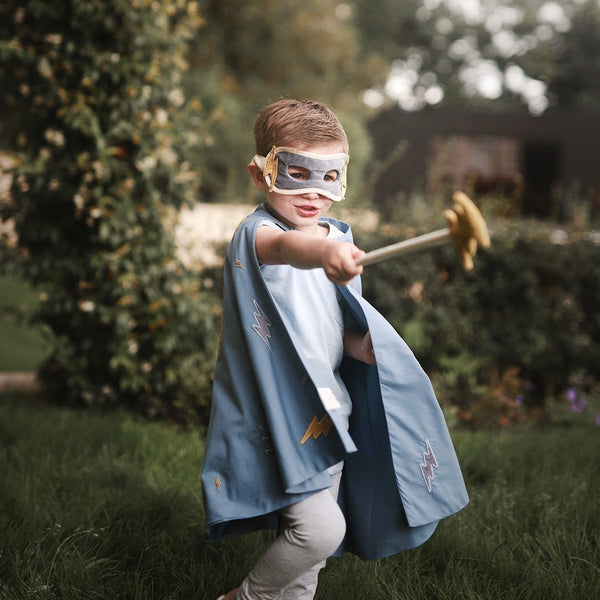 Little boy wearing a superhero dressing up costume made up of mask, cape and wand